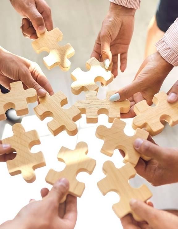Multiple hands holding puzzle pieces
